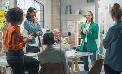 Female Business Coach for Company Management Explains How to Train your Team Efficiently in a Workshop Inside Creative Office. Woman Trainer Writing on Whiteboard and Training Interactive Employees
